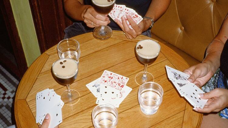 A group of people playing cards while drinking espresso martinis.